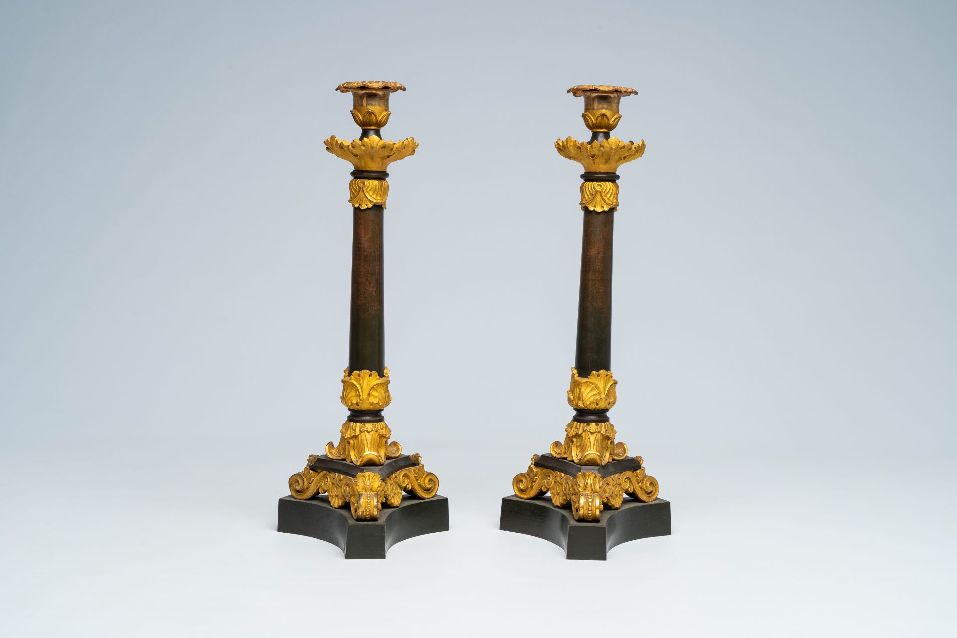 A pair of French gilt and patinated bronze candlesticks with floral design, 19th C.