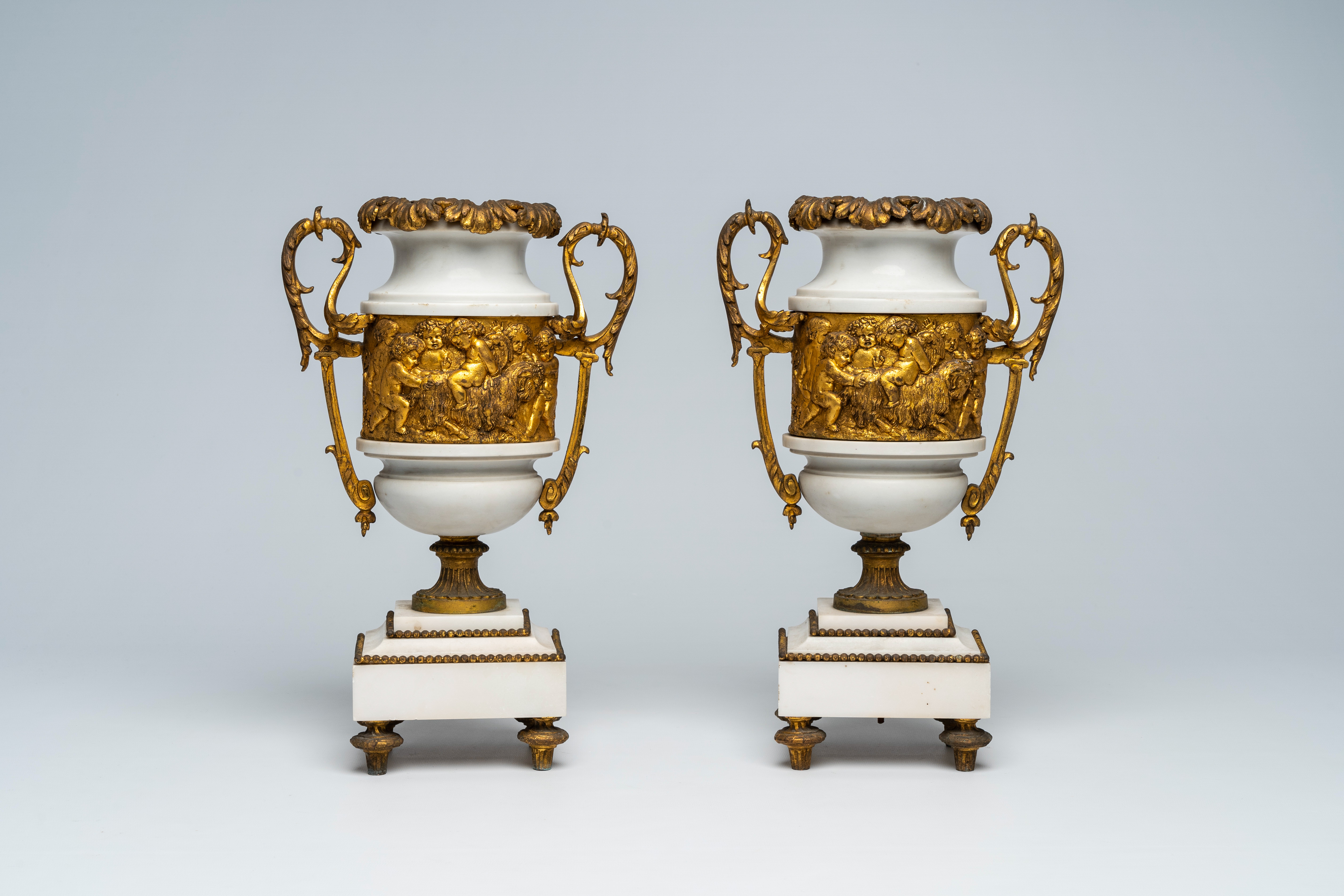 A pair of French gilt mounted white marble vases with relief design of putti, goats and Bacchus them