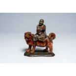 A Chinese soapstone 'arhat on lion' sculpture with wooden stand, 19th C.