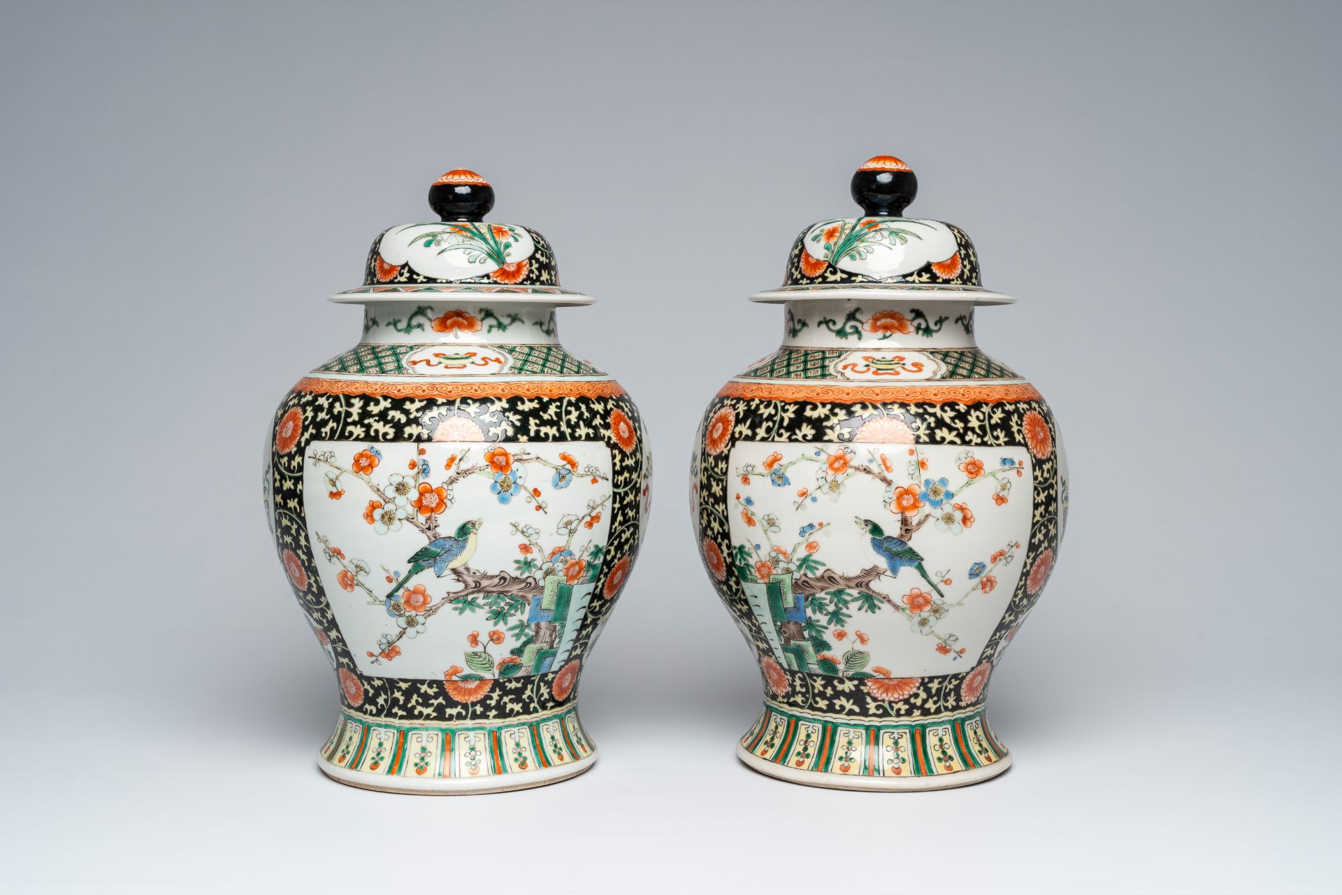 A pair of Chinese famille verte vases and covers with birds on blossoming branches, 19th C.