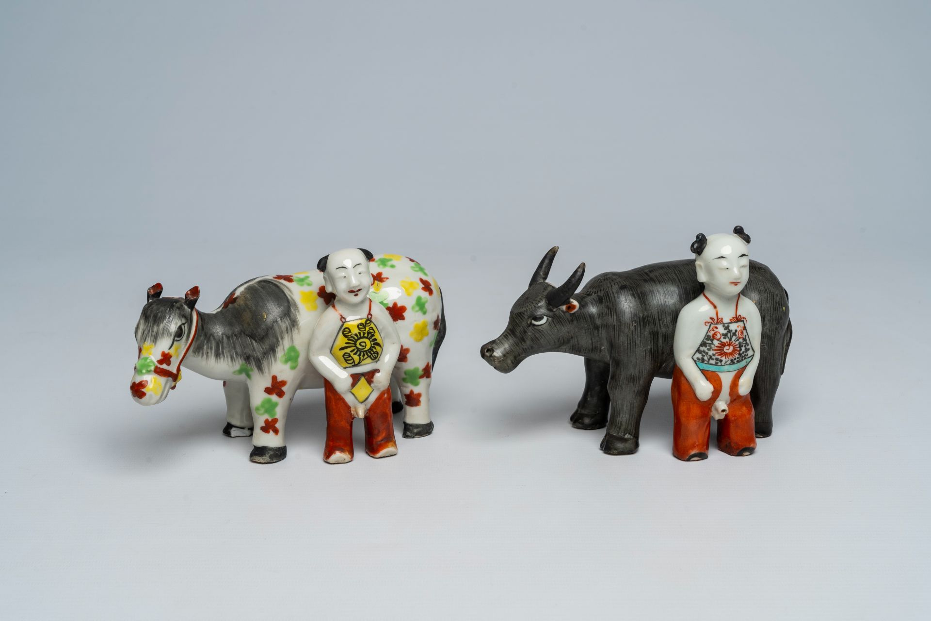 Two Chinese porcelain groups with a buffalo and a donkey with a boy, 19th/20th C.