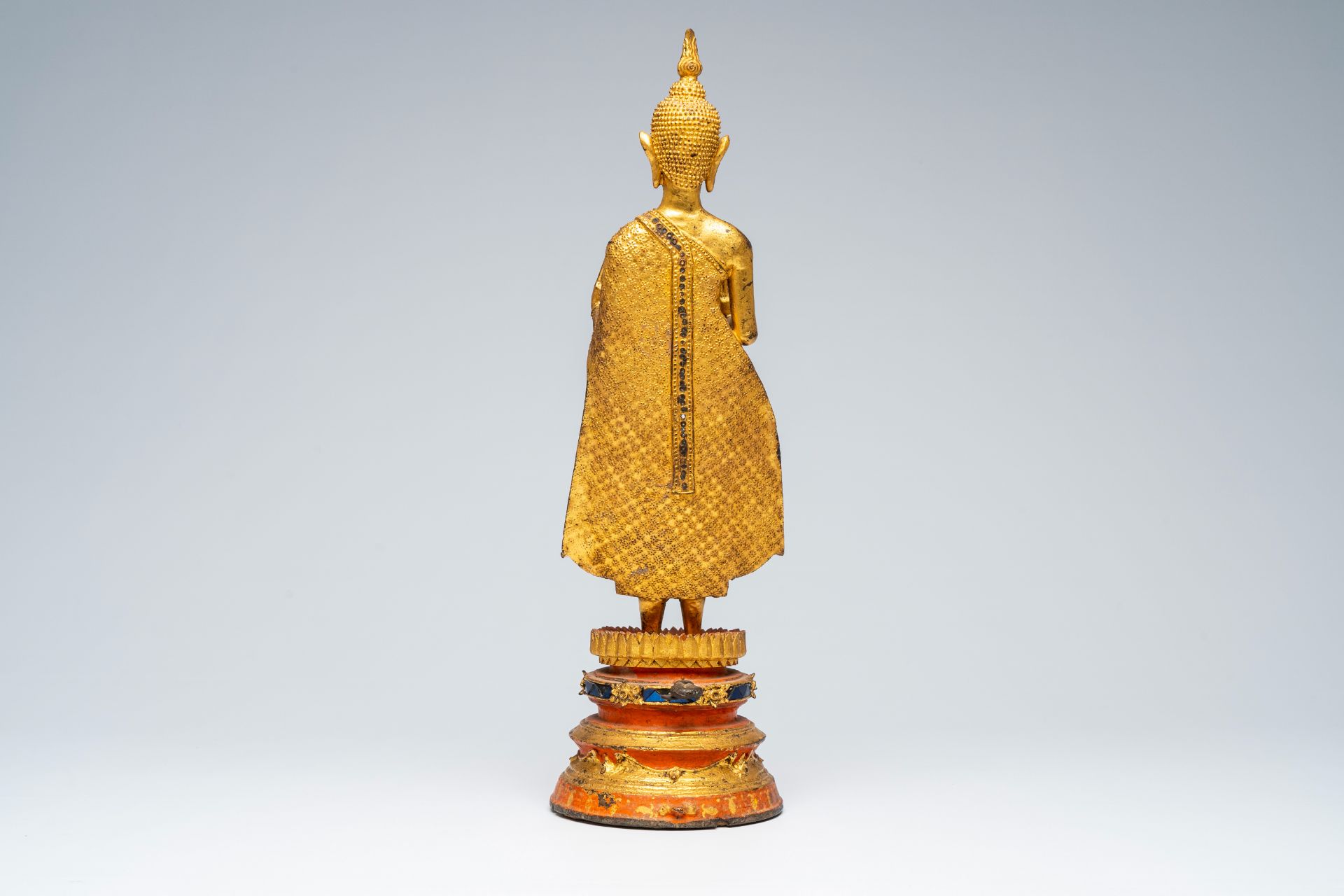 A Thai gilt bronze figure of a standing Buddha on a polychrome painted and glass inlaid metal base, - Image 4 of 8