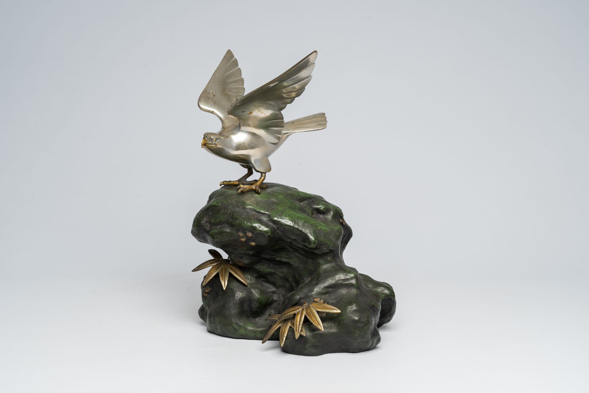 A Japanese patinated and silver-plated metal okimono of an eagle on a rock, signed Hidemasa, 20th C.