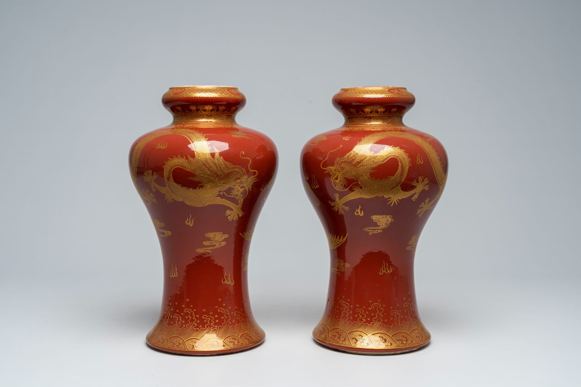 A pair of Chinese monochrome red vases with a gilt 'dragon and phoenix' design, 19th/20th C.