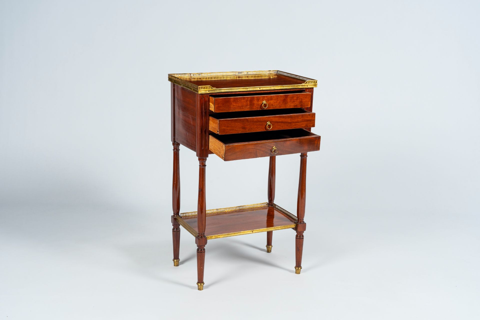 A French mahogany gilt brass mounted side table with three drawers, late 19th C.