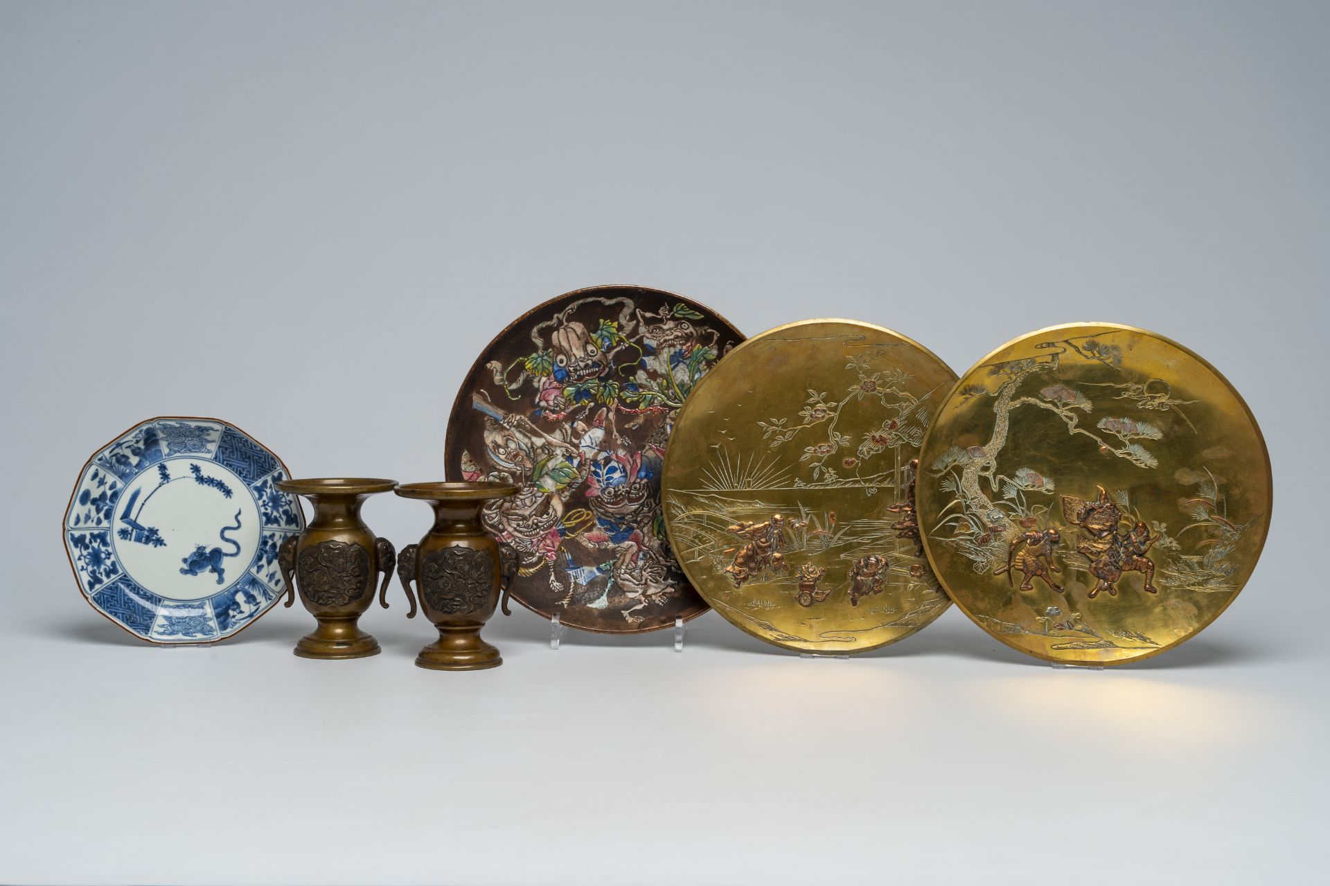 A pair of Japanese bronze vases, two mixed metal chargers with relief design, a blue and white dish