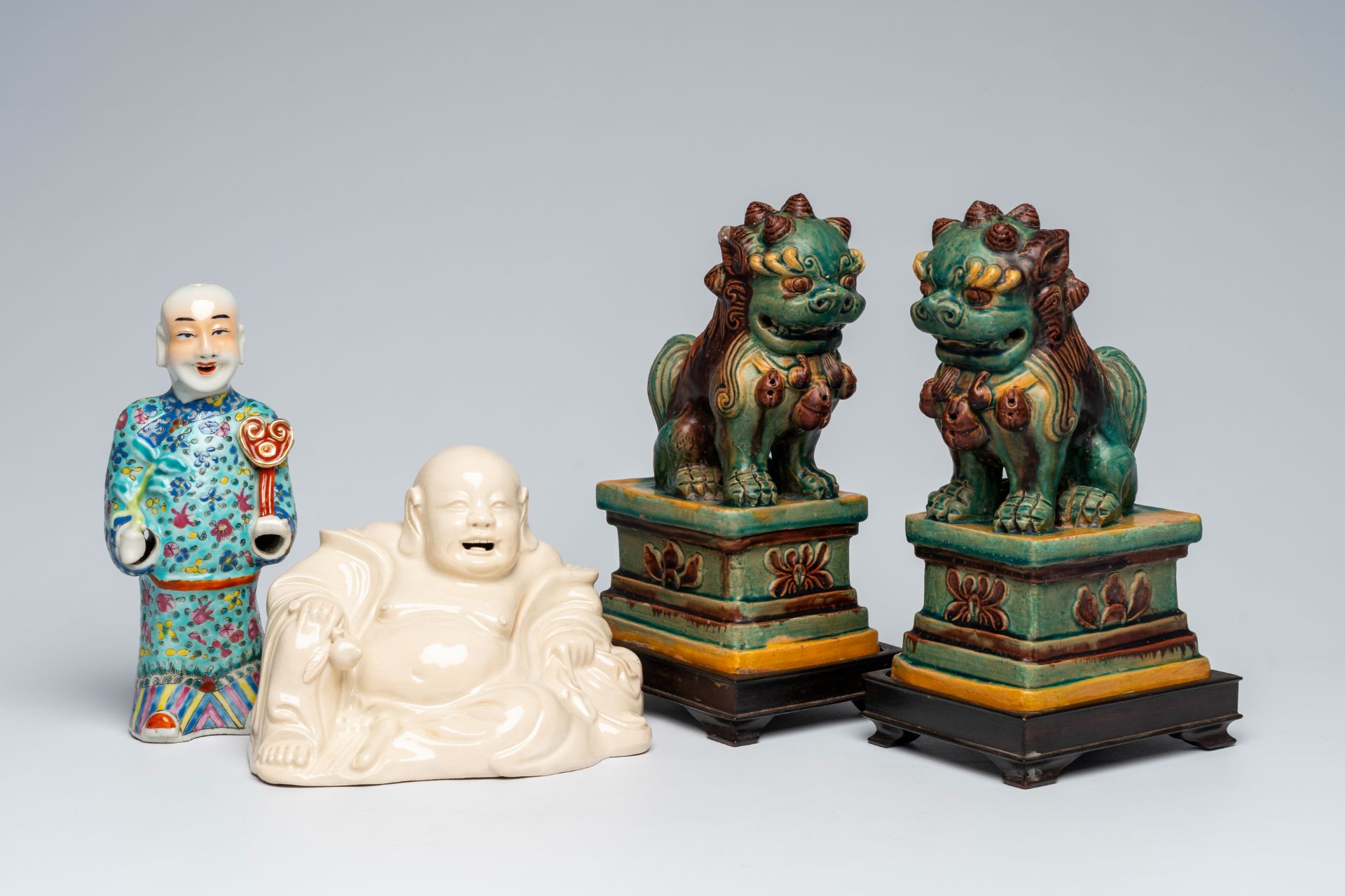 A Chinese blanc de Chine figure of Buddha, a pair of sancai glazed Buddhist lions and a famille rose