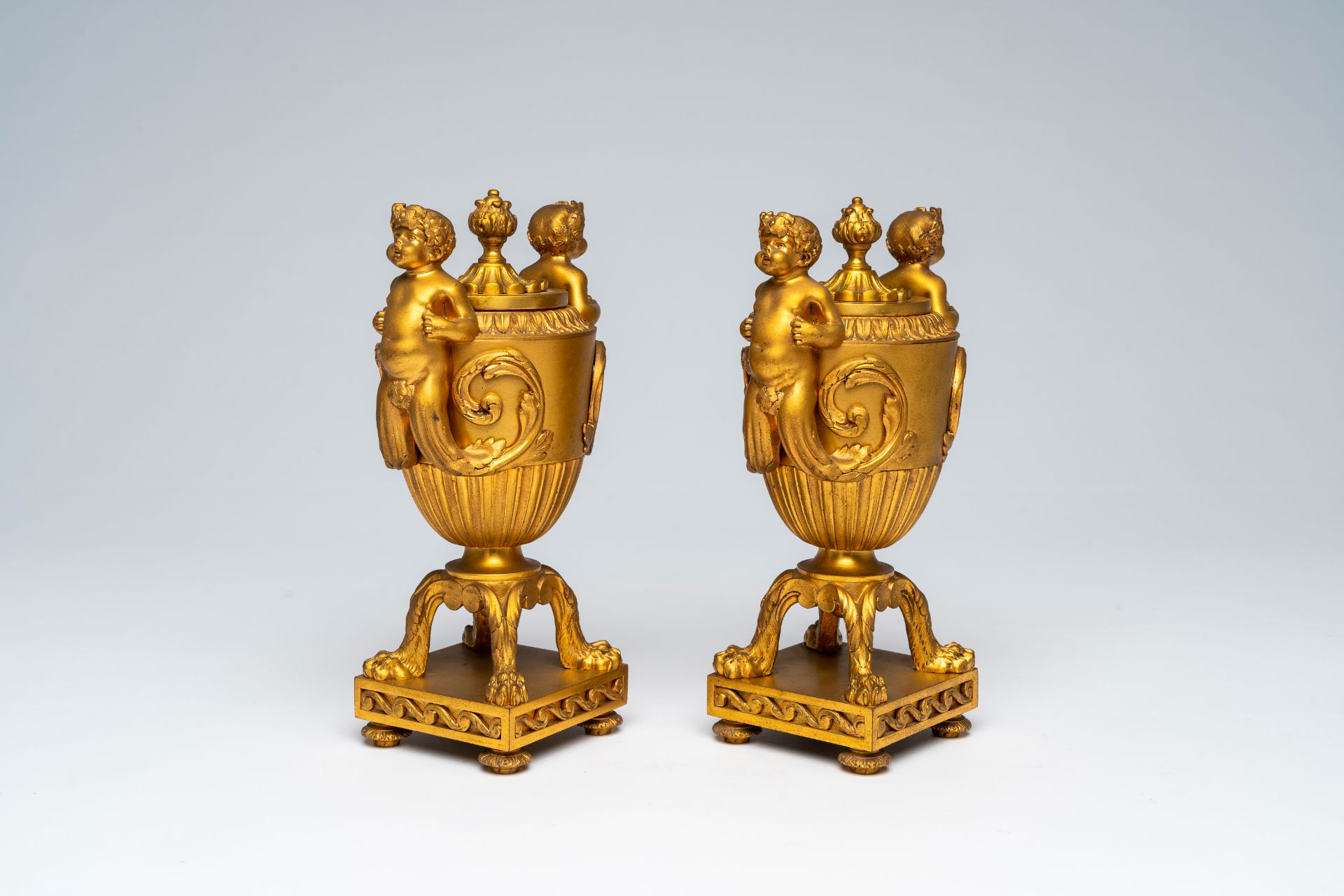 A pair of French gilt bronze vases and covers with bacchantes and lion's feet convertible into candl