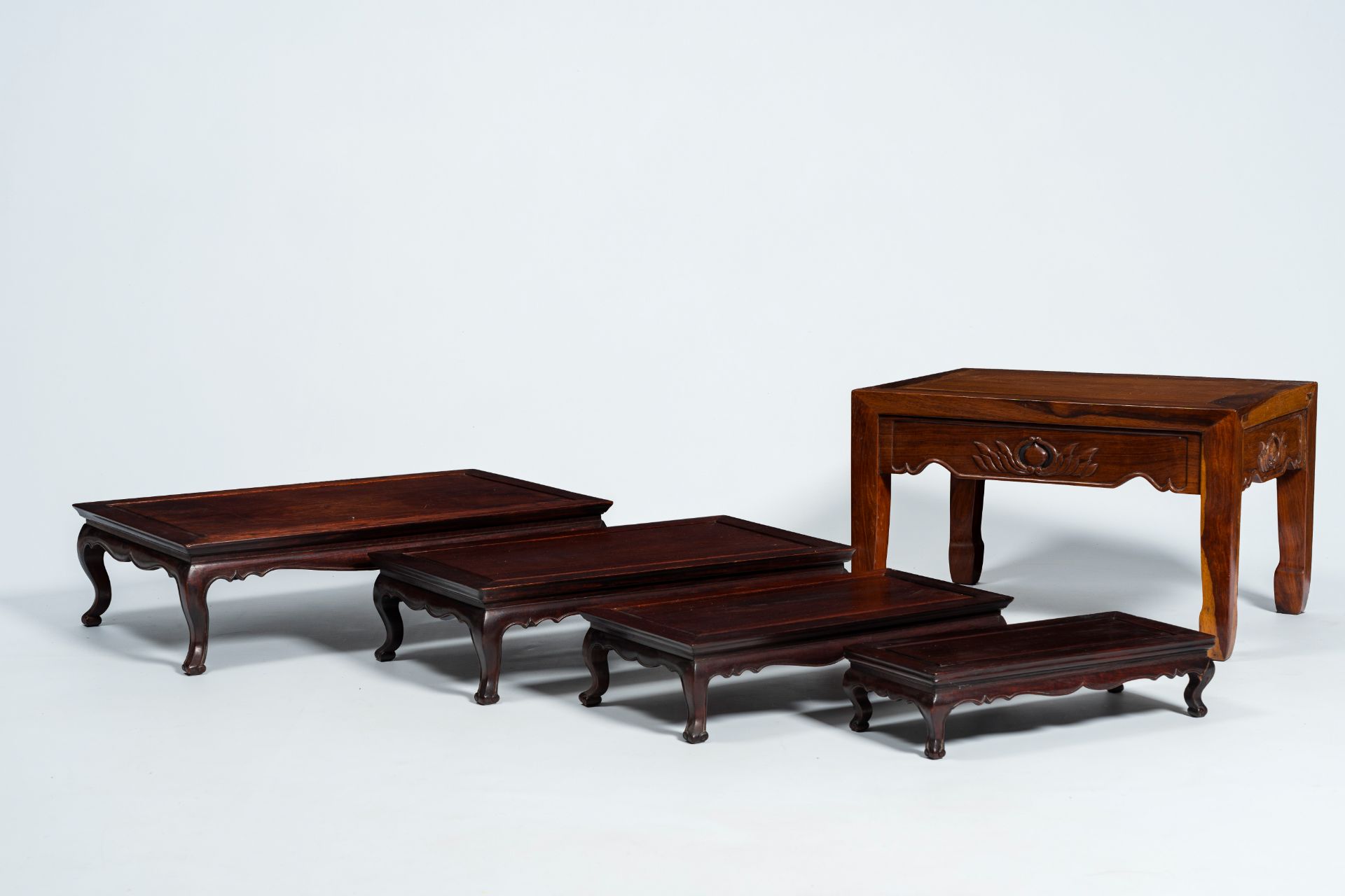 Four Chinese rectangular wood nesting tables and a side table with floral design, 20th C.