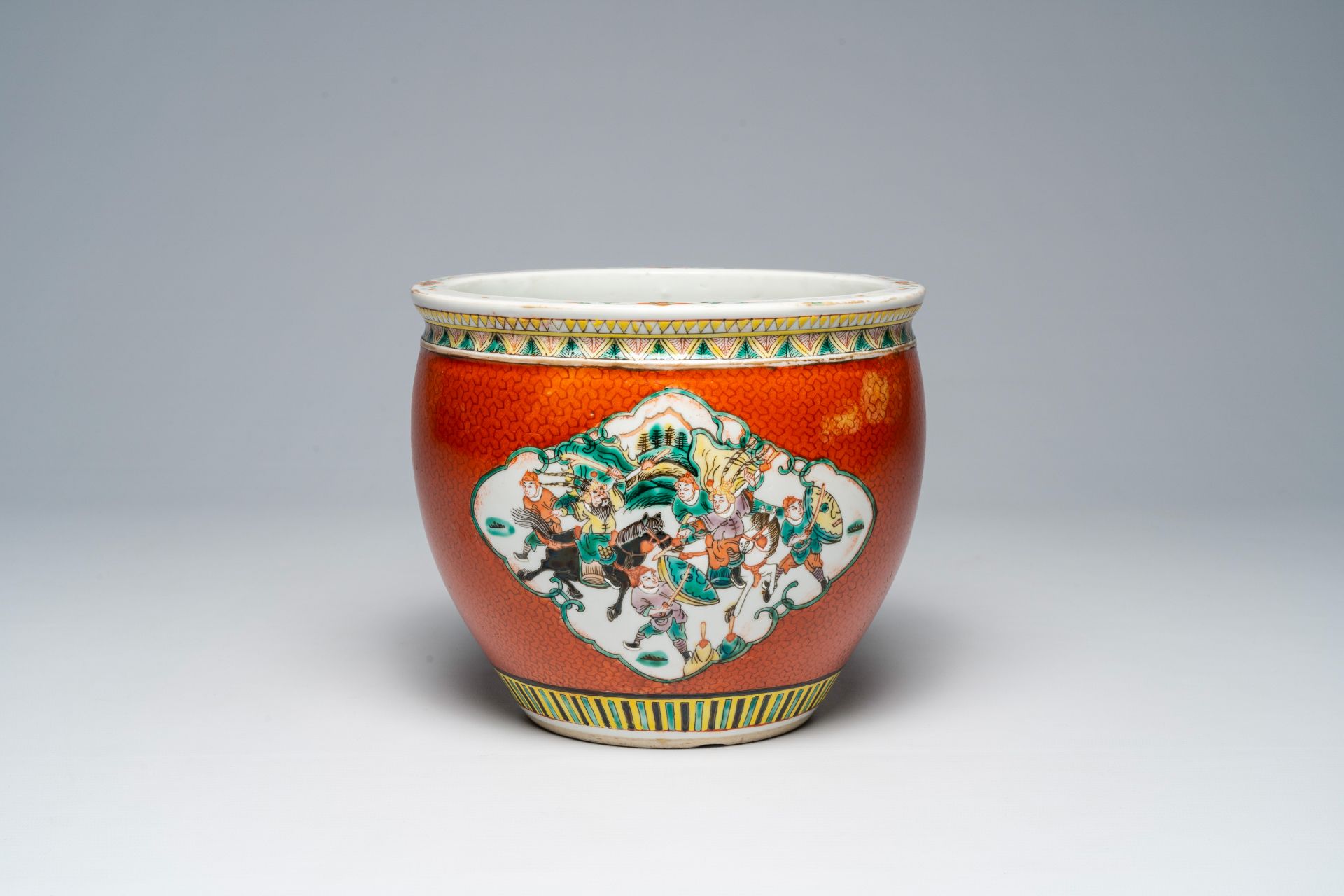 A Chinese red coral ground famille verte jardiniÃ¨re with warrior and palace scenes, 19th C.