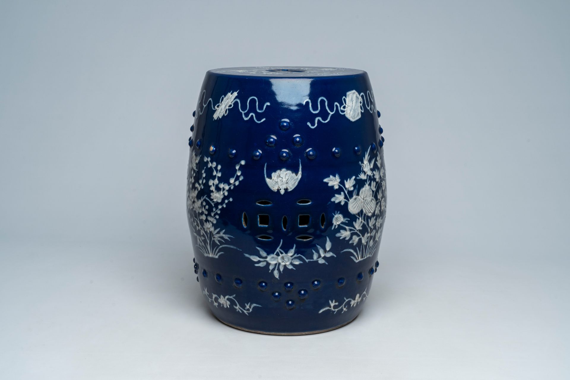 A Chinese slip-decorated blue ground garden seat with floral design, 19th C.