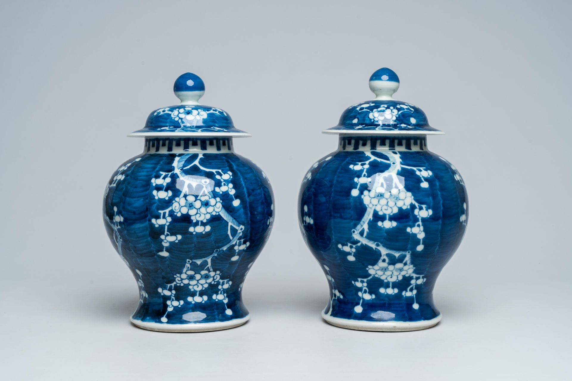 A pair of Chinese blue and white prunus on cracked ice ground vases and covers, 19th C.