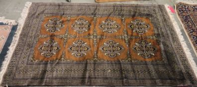 Eastern brown ground rug with two rows of four floral cross motifs, central hooked diamond border