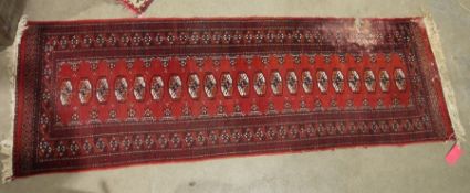 Eastern red ground rug of one row of 22 elephant foot gulls and geometric border 245 x 79 cm