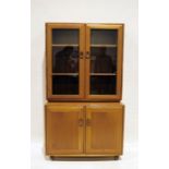 Mid-century modern Ercol light elm bookcase cabinet, the two glazed doors with shelves, the base