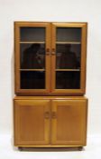 Mid-century modern Ercol light elm bookcase cabinet, the two glazed doors with shelves, the base