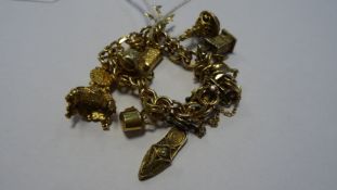 Rolled gold charm bracelet of double flattened-oval links and hung with 9ct gold charm of rococo