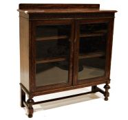 20th century oak display cabinet with two glazed doors enclosing shelves, on turned and block