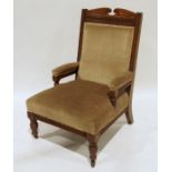 Edwardian oak-framed armchair with pale brown upholstered seat, back and armrests, on turned front