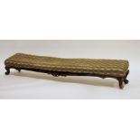 Narrow low footstool upholstered and on carved framed and squat cabriole legs, 134cm wide