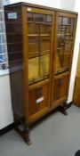 Early 20th century oak display cabinet with astragal-glazed door enclosing shelves, on turned and