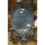Dressing table mirror, the oval plate glass in brass foliate frame with two integral candlesticks,