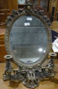 Dressing table mirror, the oval plate glass in brass foliate frame with two integral candlesticks,