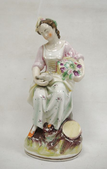 Staffordshire pottery figure of a lady vintner, late 19th century, she modelled seated holding a