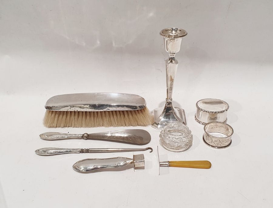 Assorted silver wares to include two napkin rings, silver-backed brush, weighted candlestick,
