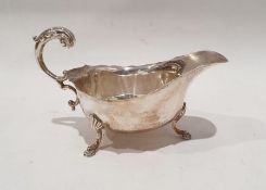 Silver sauce boat with serpentine everted rim, free C-scroll handle, shell and step pad feet,