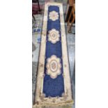 Modern blue ground runner with three central floral motifs flanked by foliate scroll border 348cm