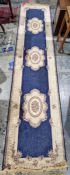 Modern blue ground runner with three central floral motifs flanked by foliate scroll border 348cm