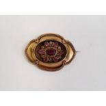 Victorian gold-coloured metal and pink stone brooch, shaped oval, the centre set with faceted ruby/