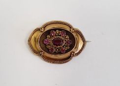 Victorian gold-coloured metal and pink stone brooch, shaped oval, the centre set with faceted ruby/