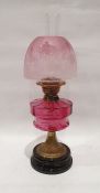 Duplex paraffin lamp with pink glass shade and well, brass body and on a circular base, approx. 58cm