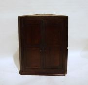 Georgian oak wall-hanging corner cupboard, the two panelled doors enclosing shelves and four short