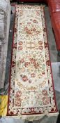 Large cream ground runner with several floral medallions flanked by floral border 304cm X 99cm