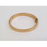 Gold-coloured metal hinged bangle with safety chain, 30g approx.