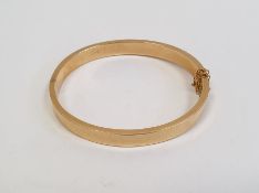 Gold-coloured metal hinged bangle with safety chain, 30g approx.
