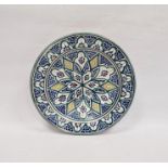 Middle Eastern glazed earthenware charger with stylised flowerhead decoration on a blue-ground, 40cm