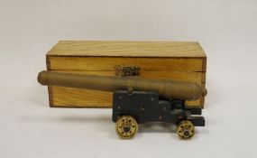 Brass model of a cannon on wooden base with brass wheels, housed in oak case, the barrel approx.