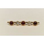 Gold-coloured metal, garnet and moonstone brooch set three cabochon garnets and two cabochon