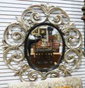 20th century oval mirror with bevel edge, in a moulded silver-coloured sprayed scrolling frame,