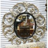 20th century oval mirror with bevel edge, in a moulded silver-coloured sprayed scrolling frame,