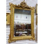 Gilt wall mirror in the rococo taste with ornate pierced floral and foliate pediment, foliate scroll