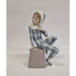 Lladro figure of boy wearing harlequin suit seated on box initialled B, 20.5cm high