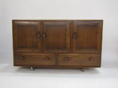 Ercol elm sideboard with oval dished handles, 3 cupboard doors above 2 drawers on castors, 75.5cm