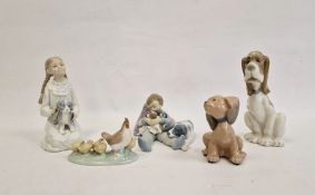 Nao girl kneeling with puppy, Lladro figure group, boy reclining on cushion with dog and puppies,