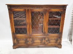 20th century oak cabinet, the moulded carved cornice above three leaded glazed doors enclosing