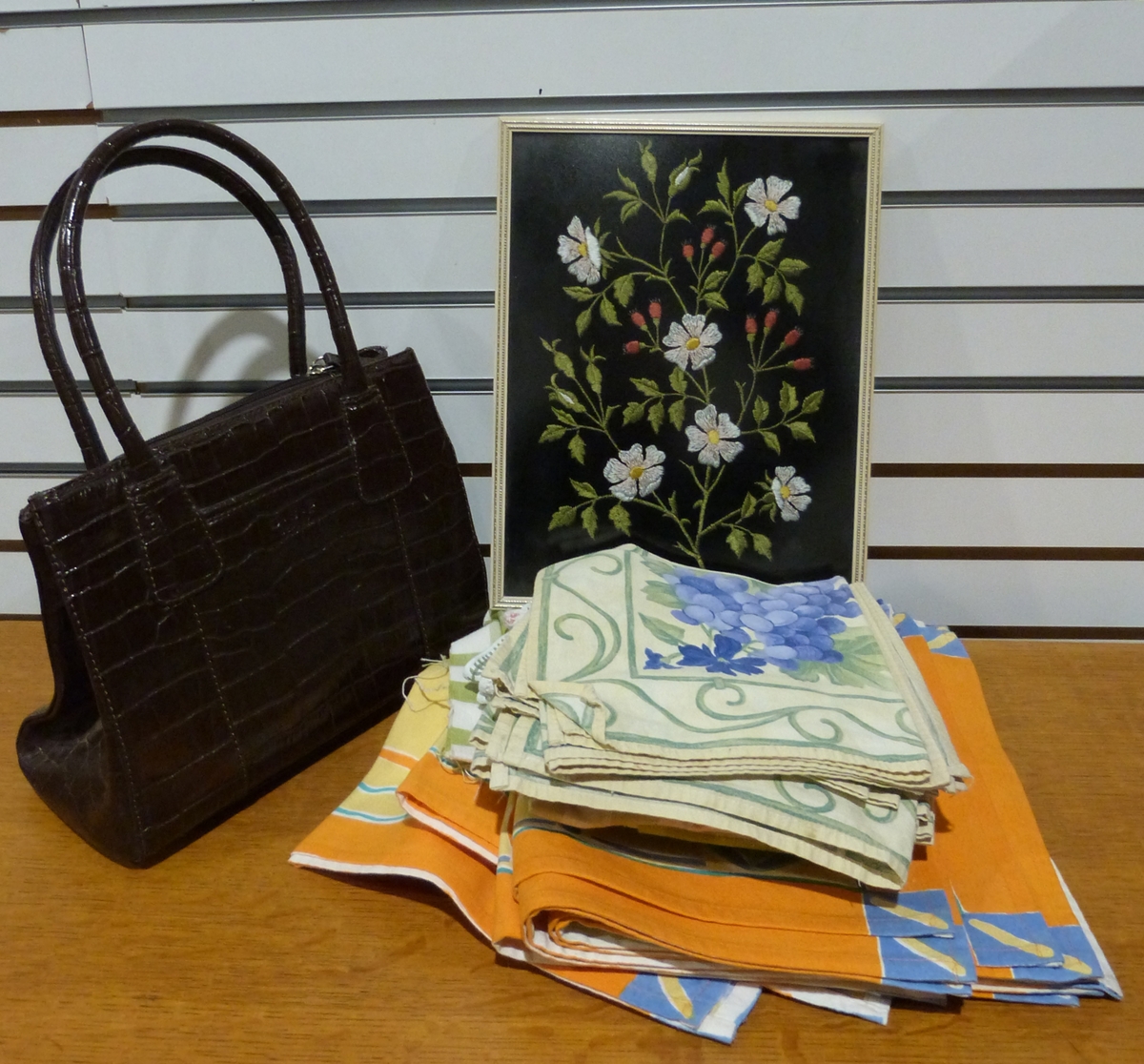 Three boxes of assorted linen and tablecloths and a leather faux-crocodile skin handbag by Osprey